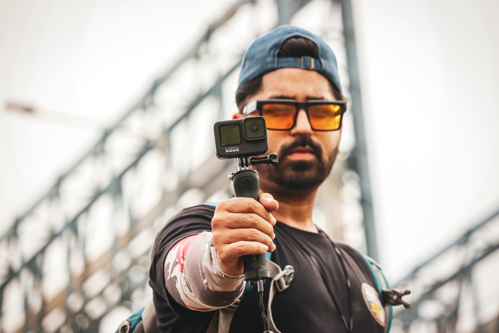 Asian man with GoPro filming outdoors, wearing sunglasses and a black shirt.